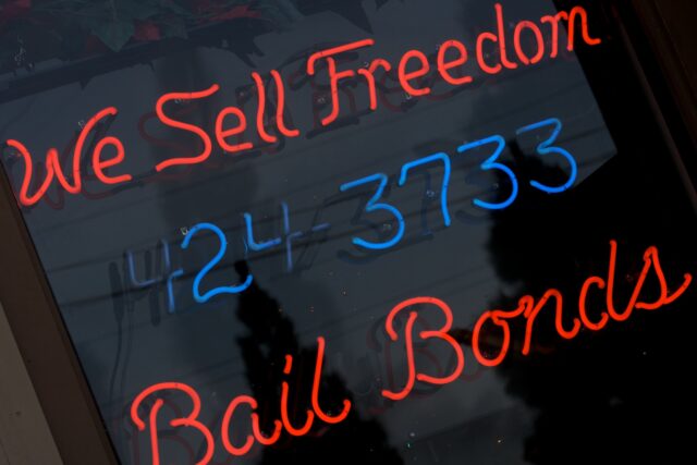 A neon sign in a bail bondsman’s window reads “We sell freedom, 424-3733, Bail Bonds.”