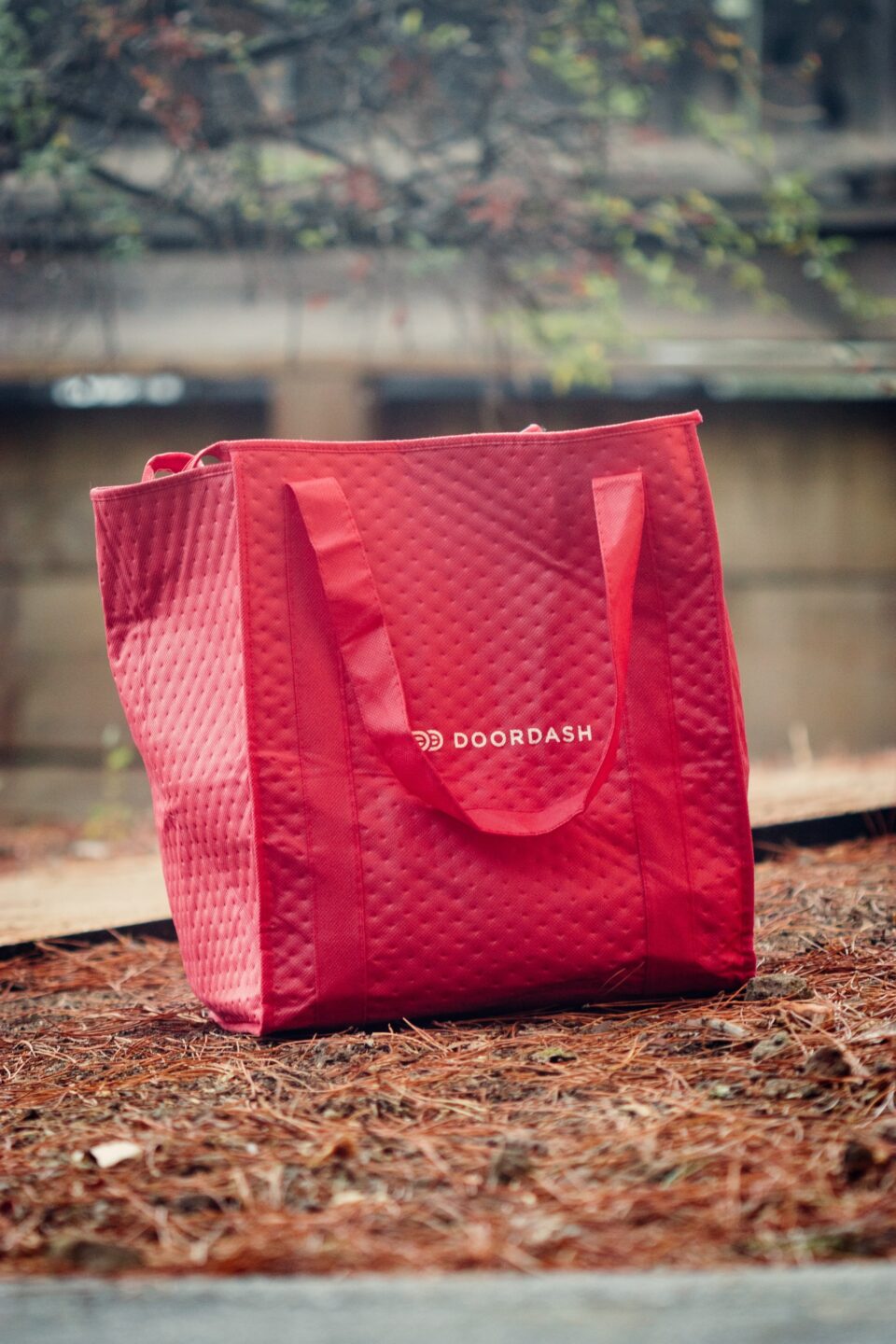 A DoorDash delivery bag sitting on the ground.