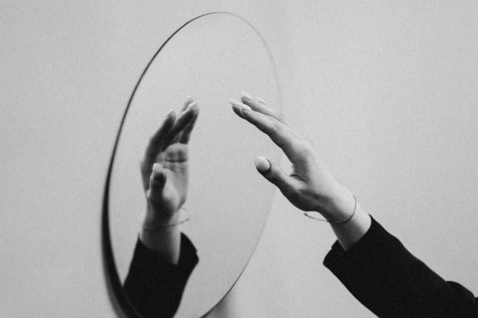 Black and white image of a handing reaching out to a mirror 