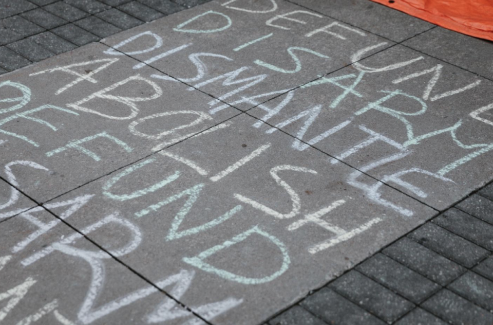 “Defund, Disarm, Dismantle, Abolish” written in chalk on a sidewalk