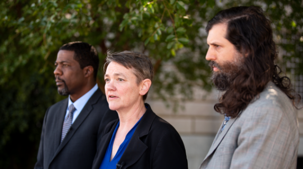 Maria Morris, flanked by two men, standing in public Source: Southern Poverty Law Center.