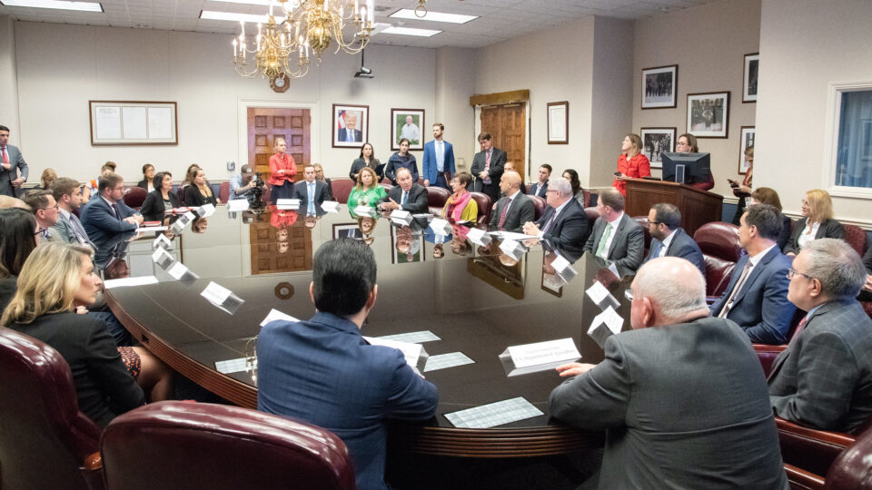 Representatives of AND, the University of Arkansas, Campus Kitchens Projects, as well as the American Farm Bureau Federation, dressed in suits and other formal attire around an oval table, meet as part of a USDA panel