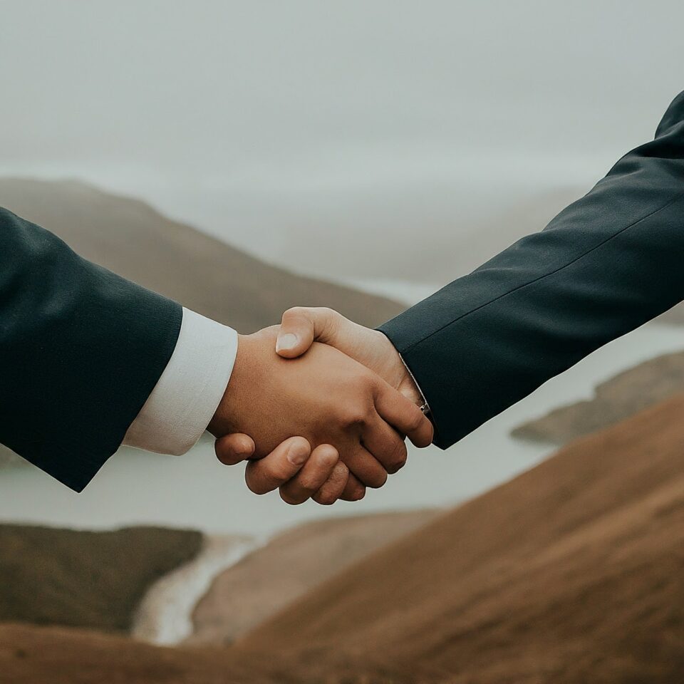 A handshake is depicted in front of a Western river landscape