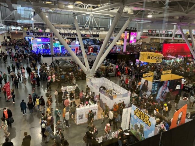 Convention attendees and booths on the main floor of the PAX East 2024 video game and board game convention.