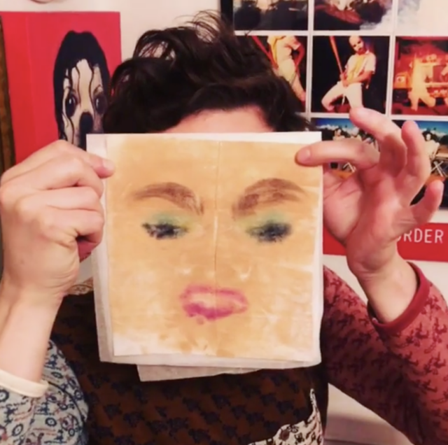 A person holds up a smudged face of makeup on a makeup wipe.