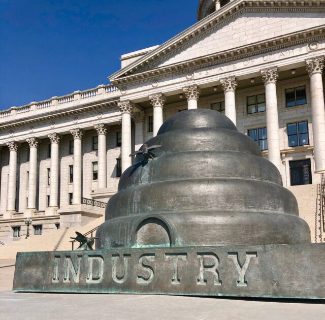 An image of a beehive sculpture with the word “Industry” inscribed in front of the Utah State Capitol.