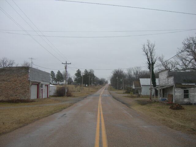 Empty rural road through a small town on a gray day.