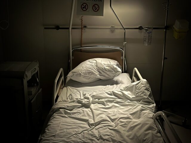 Empty hospital bed with dim overhead lighting