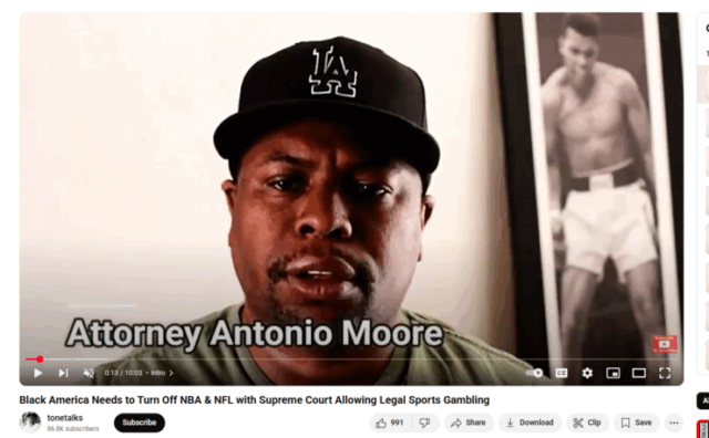 A freeze frame image of Attorney Antonio Moore on his YouTube talk show. He is a Black man, wearing a black “LA” baseball cap, pictured from the shoulders up.