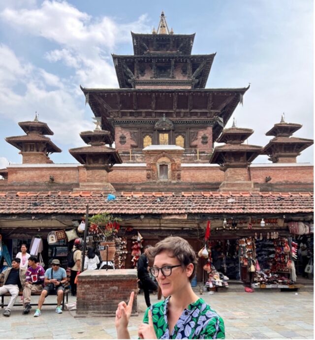 A photo of Erin Thompson pointing back at Taleju Bhawani Temple.