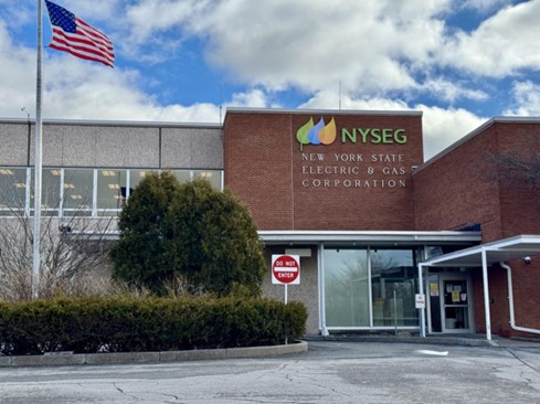 The front of the NYSEG building with an American flag and a Do Not Enter traffic sign.