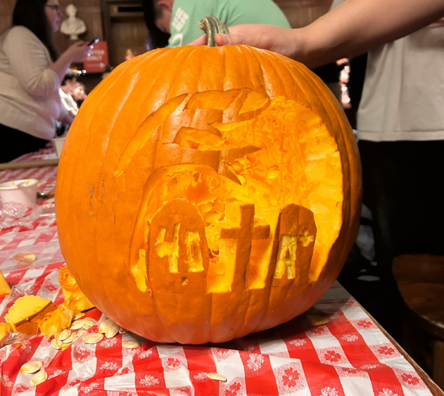 A carved pumpkin depicting a graveyard with headstones that say 4.0 and A+.