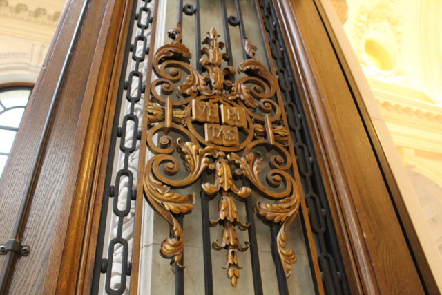 A carved wooden emblem of Harvard’s shield which says “Veritas” 
