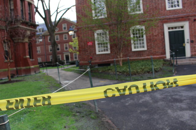 A picture of Massachusetts Hall with yellow caution tape in the foreground 