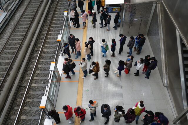 People on their phones while waiting in line for a train.